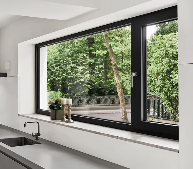   Cuisine contemporaine avec fenêtre aluminium Schüco à cadre noir : apport de lumière naturelle généreux et vue apaisante sur le jardin.
